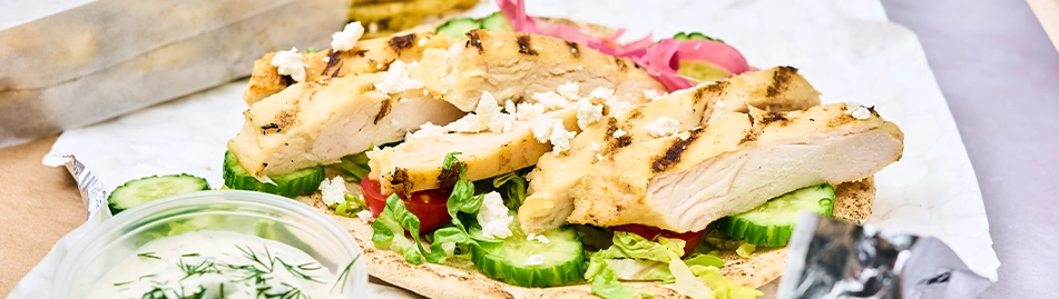 A sliced, unbreaded chicken filet atop pita bread