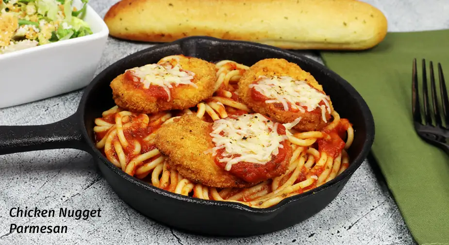 Chicken nuggets over spaghetti in a small cast iron pan