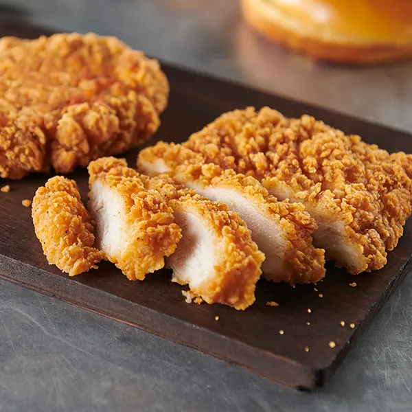 A crispy chicken filet sliced on a cutting board