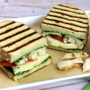 A chicken sandwich with panini grill marks on a metal tray