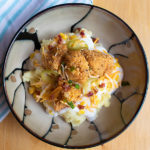 Mashed potatoes, `boneless chicken wings, cheese, and toppings on a bowl