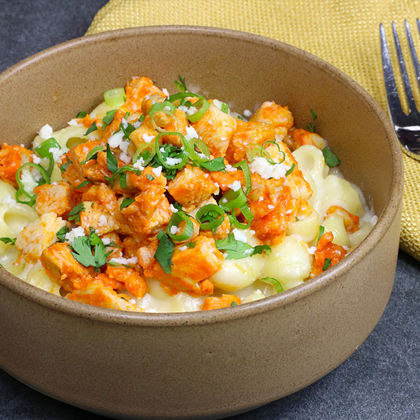 A bowl of mac n cheese, topped with Buffalo-Style Diced Chicken