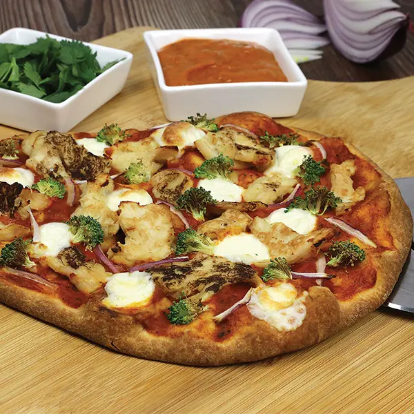 Butter chicken pizza on a wood cutting board