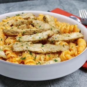 A dish of pasta topped with sliced chicken