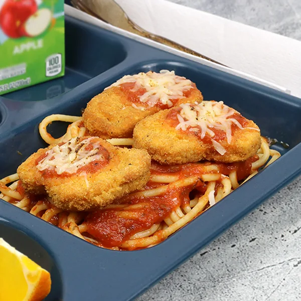 A school lunch tray with spaghetti noodles topped with chicken nuggets as a chicken parm dish