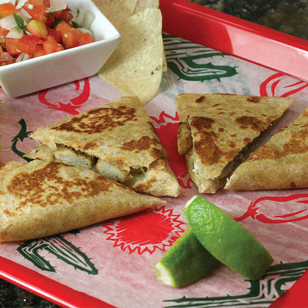 A chicken nugget quesadilla sliced into four pieces on a tray