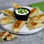 A plate with chicken pierogi and sour cream