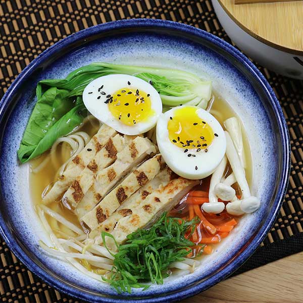 Bowl of ramen noodles topped with sliced chicken and hard cooked eggs