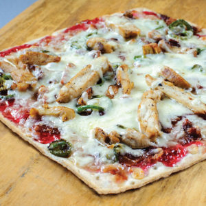 Flatbread pizza topped with raspberry jam, chicken, and Monterey jack cheese