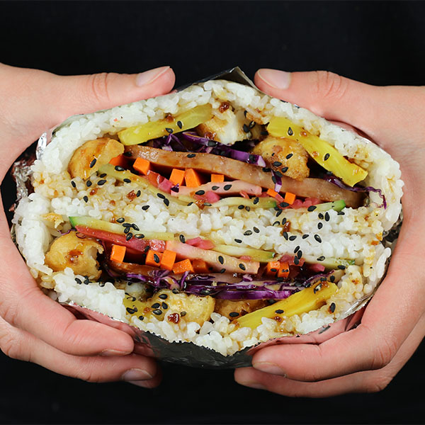Hands holding a sushi sandwich