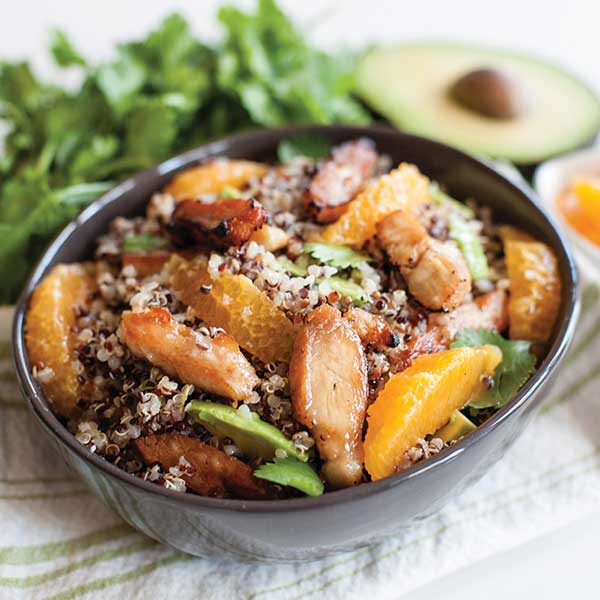 A chicken, quinoa, avocado, and orange salad in a bowl