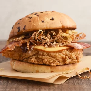 Chicken sandwich with onion straws, bacon, BBQ sauce, and cheese