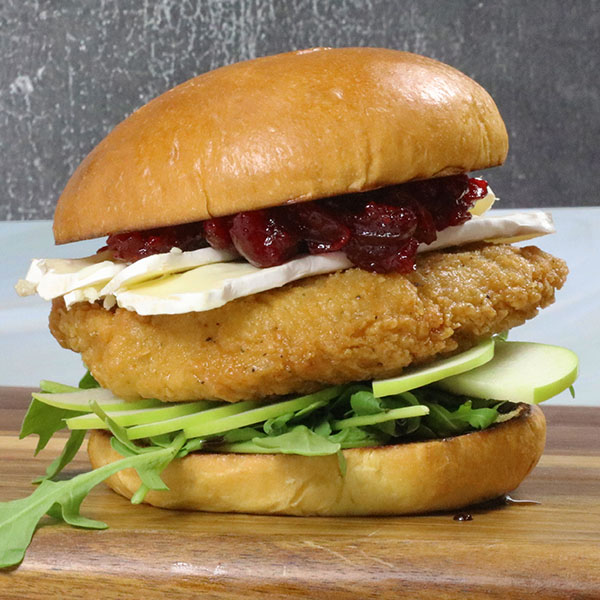 Crispy chicken filet, arugula, sliced apples, brie, and cranberry jam on a sandwich