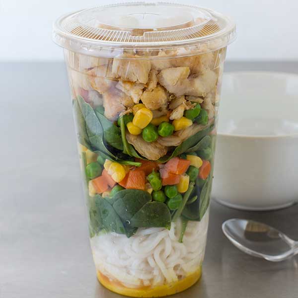Cup filled with diced chicken, veggies, and noodles