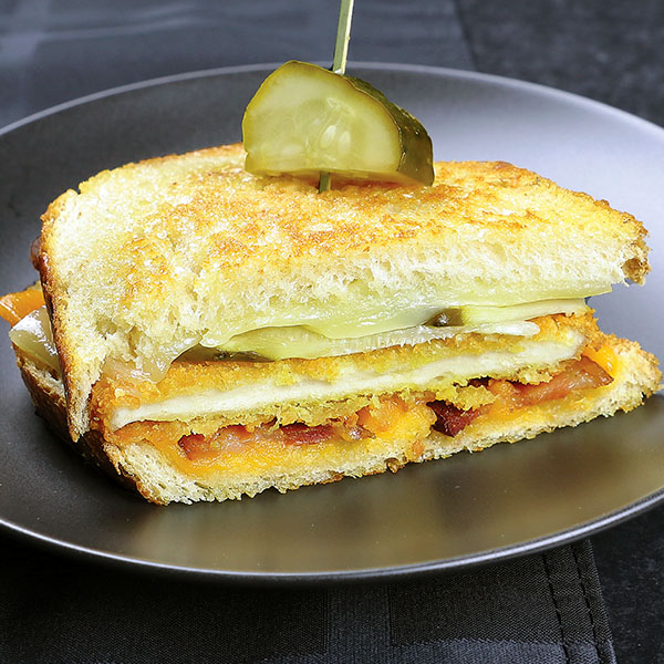 Chicken pattie on sour dough bread with cheese, bacon, and dill pickle