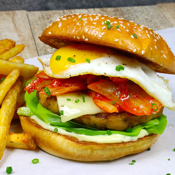 Chicken burger with egg, kimchi, and lettuce, and fries on the side.
