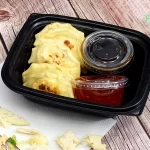 A to-go box of chicken potstickers with sauce