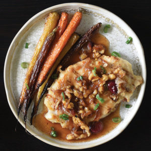 Plate with chicken filet topped with walnuts, grapes, and sauce