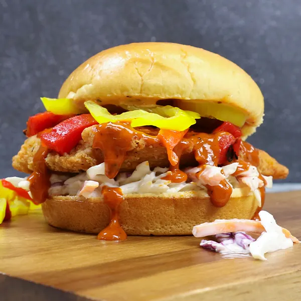 A breaded chicken sandwich with peppers and coleslaw