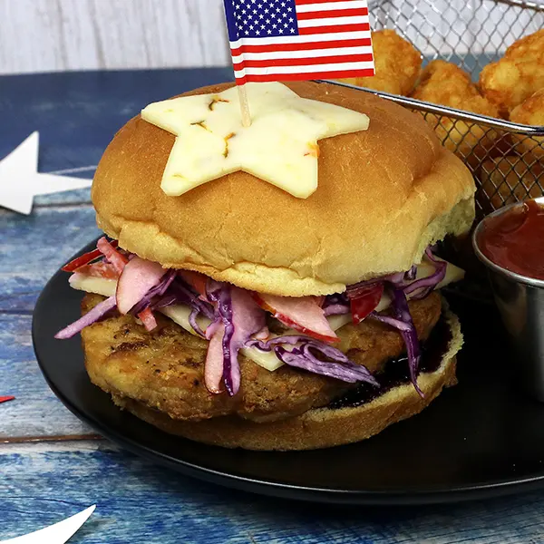 A chicken burger with apple slaw, blueberry bbq sauce, and a cheese star