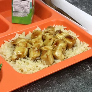 Teriyaki chicken over rice on a school lunch tray